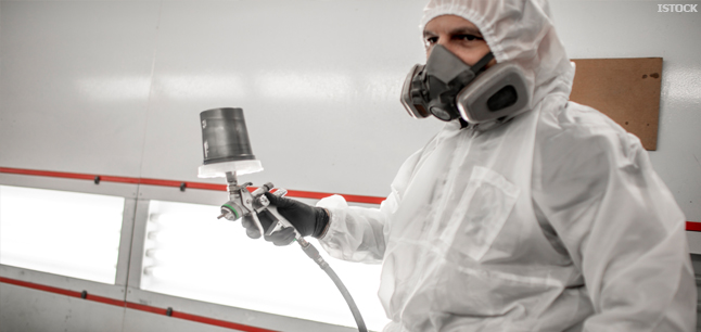 Car paint sprayer in coveralls and a breathing mask holding a paint spray gun Car paint sprayer in coveralls and a breathing mask holding a paint spray gun