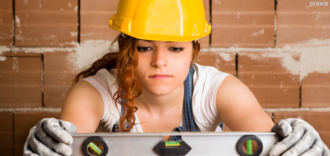 Bricklayer with spirit level wearing safety helmet and gloves Bricklayer with spirit level wearing safety helmet and gloves