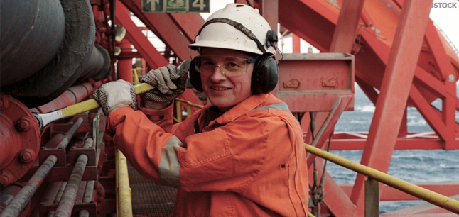 Oil worker on oil rig wearing safety equipment and coveralls