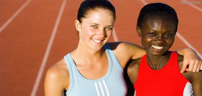 Sportswomen smiling with arms around each others shoulders