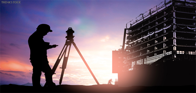 Survey engineer working in a building site at sunset